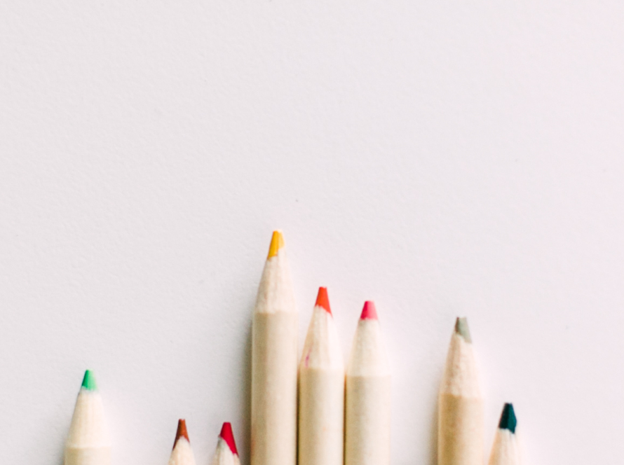 We can see an irregular row of colored pencils with an ivory background and a pink semicircle on the upper left edge.