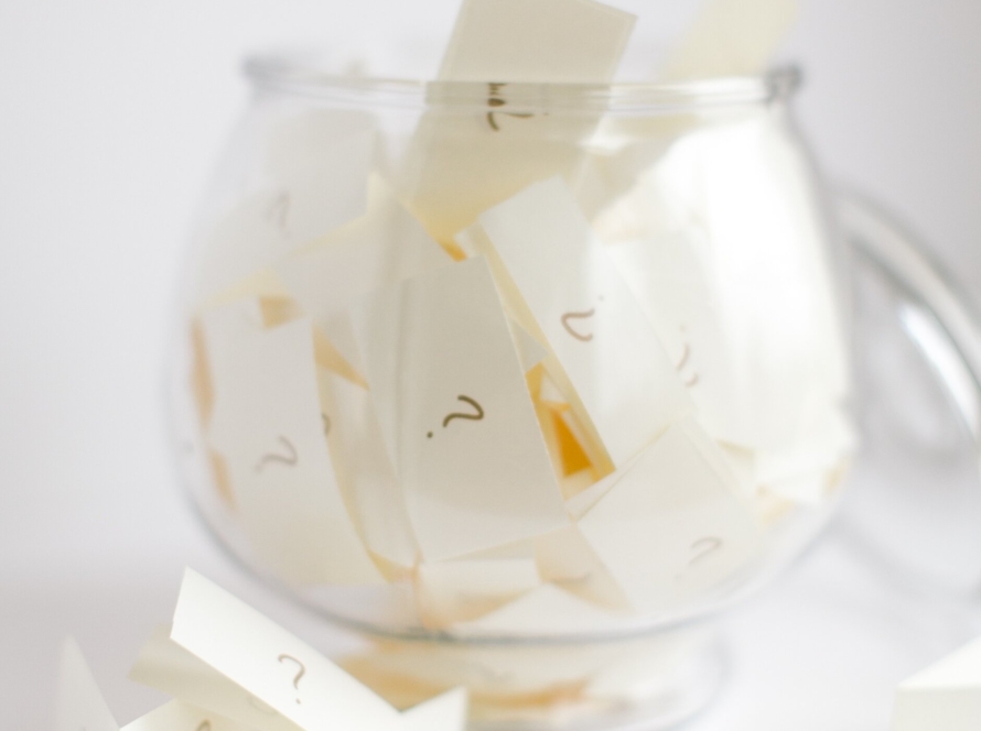 We can see in the image a crystal glass that inside keeps many small papers with the question mark.