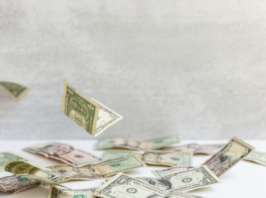 We can observe in the image, low denomination dollar bills, falling on a table.