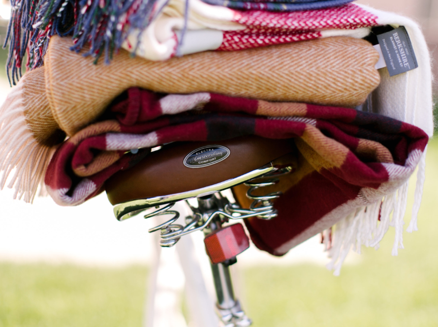 In the image we can see a white bicycle, with blankets of various colors and textures.