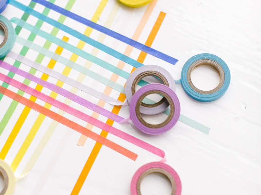In the image we can see several rolls of different colored paper tape forming intersecting lines.