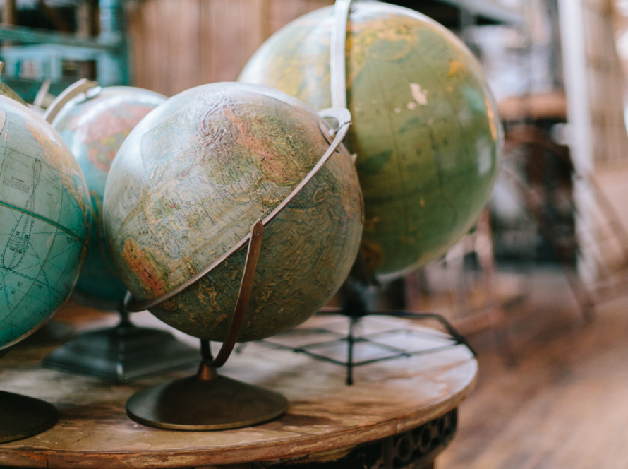 In the image we can see old globes on an old round table also, apparently located in a library