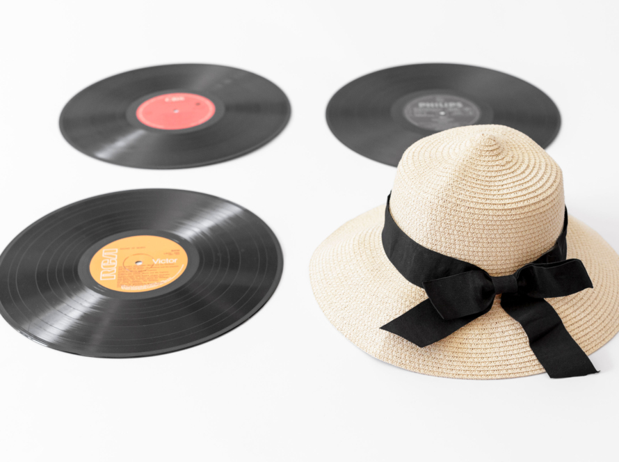 In the image we can see 3 long plays and a hat with a bow on a white background.