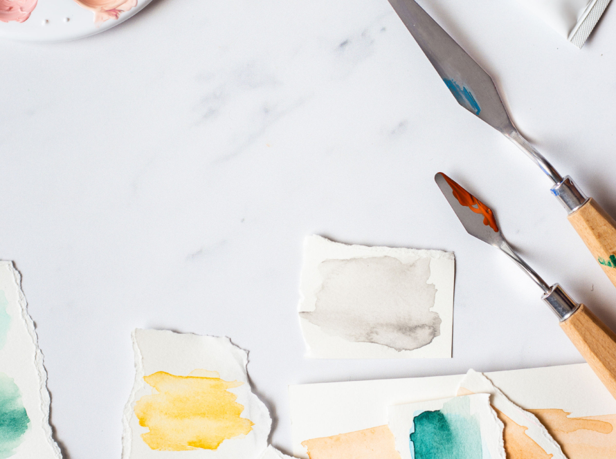 In the image, we can see a palette, brushes, and watercolors plus other artistic painting utensils.