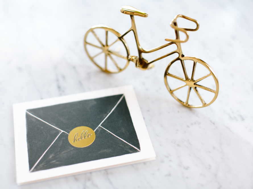 In the image we can see a bicycle and an envelope of correspondence as decoration on a desk.