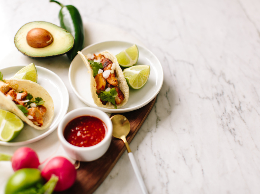 In the image, we can see tacos with salsa and lemon.