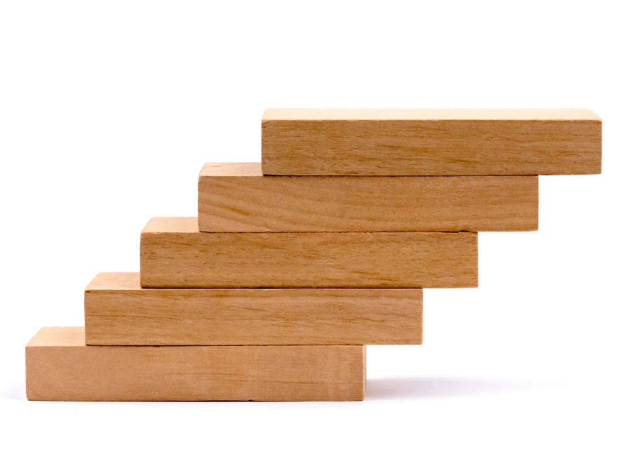 5 Blocks - like the ones used in a game of Jenga -- are stacked -- with each piece slightly moved to the right of the piece below it - resembling a staircase -- and signifying brand growth strategy has shifted in 2026.